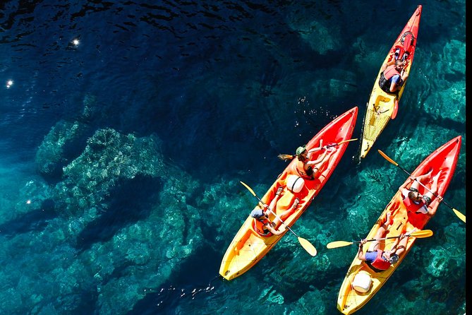 Kayaks on clear water below the Dubrovnik cliffs